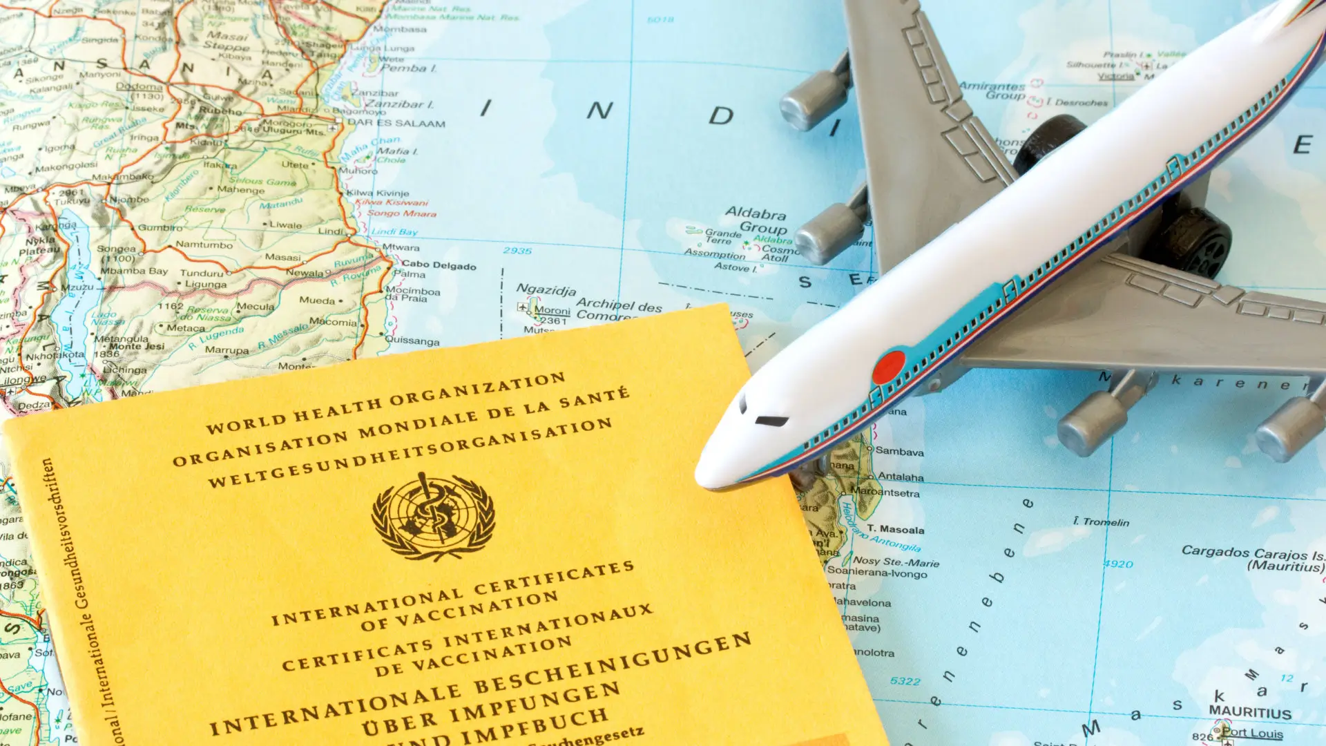 Libretto giallo del Certificato Internazionale di Vaccinazione dell'OMS con un aeroplanino su una mappa, a indicare l'importanza delle precauzioni sanitarie in viaggio verso il Vietnam.