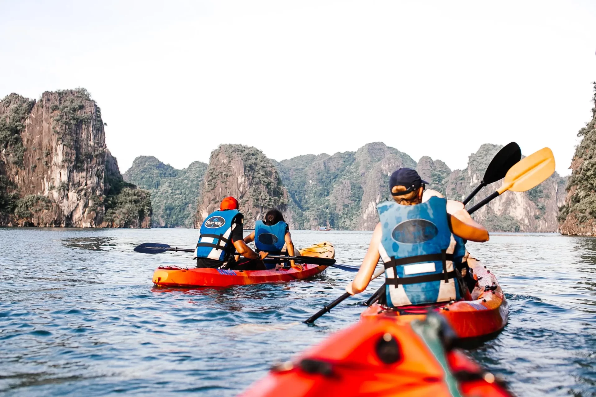 Turisti in kayak navigano tra le spettacolari isole calcaree del Vietnam, un'attività perfetta per il periodo migliore di visita.