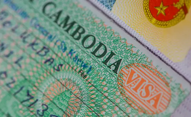 Visto turistico cambogiano timbrato su un passaporto, dettagli e timbri di sicurezza visibili.