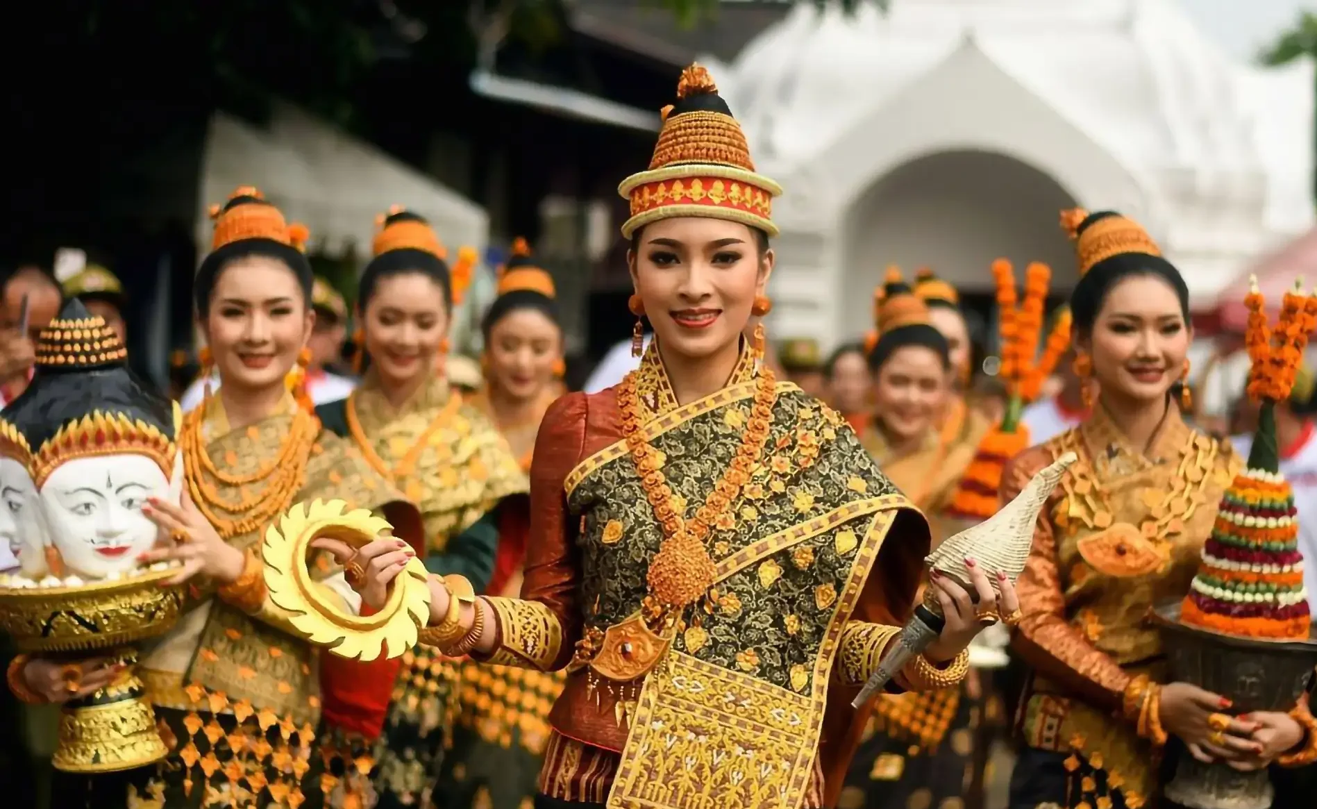 Donne laotiane in abiti tradizionali partecipano a una parata di festa, rappresentando la ricca cultura e l'eredità delle celebrazioni in Laos.