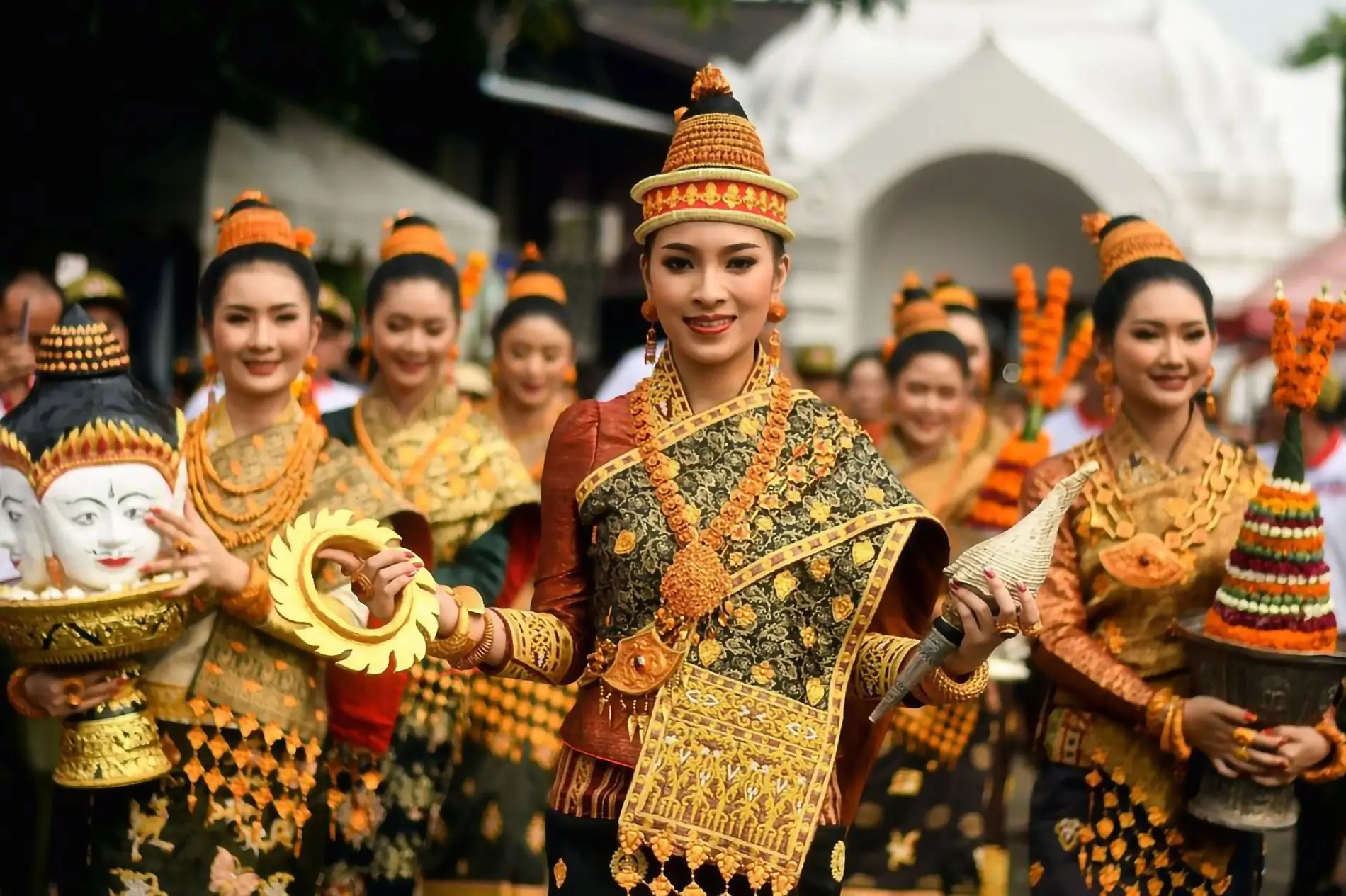 Donne laotiane in abiti tradizionali partecipano a una parata di festa, rappresentando la ricca cultura e l'eredità delle celebrazioni in Laos.