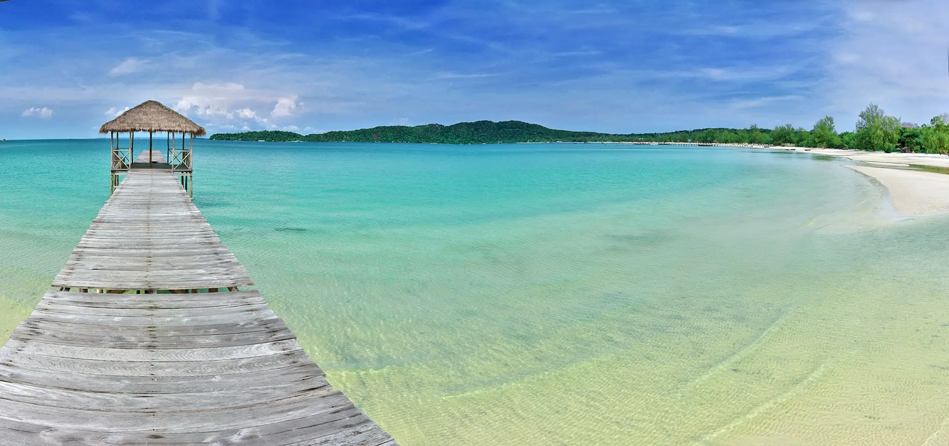 Un pittoresco pontile di legno che porta a un rifugio su acque cristalline dell'isola di Koh Rong Samloem, incarna il paradiso tropicale cambogiano per eccellenza.