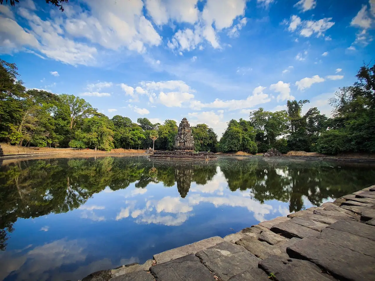 Il sereno lago del tempio Neak Pean in Cambogia riflette il cielo nuvoloso, un'immagine che invita alla tranquillità e alla scoperta spirituale, perfetta per un articolo di viaggio su quando andare in Cambogia