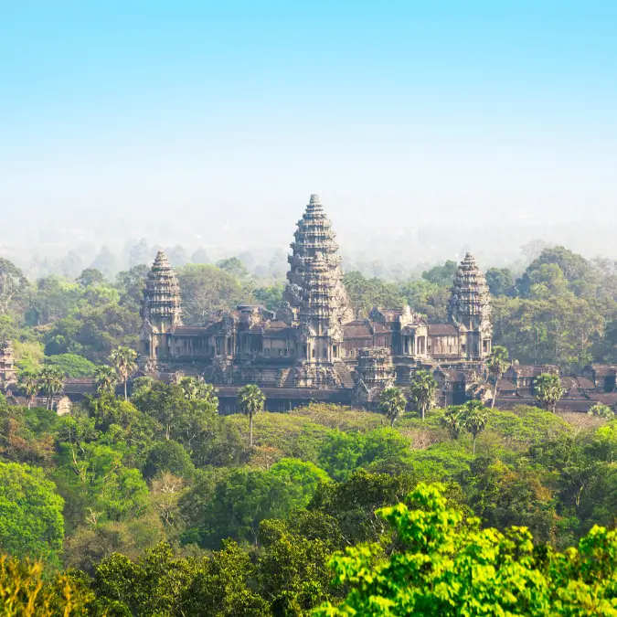 Panoramica del Tempio di Angkor Wat in Cambogia, meraviglia architettonica immersa nella giungla, con torri che si ergono verso il cielo in una giornata nebbiosa.