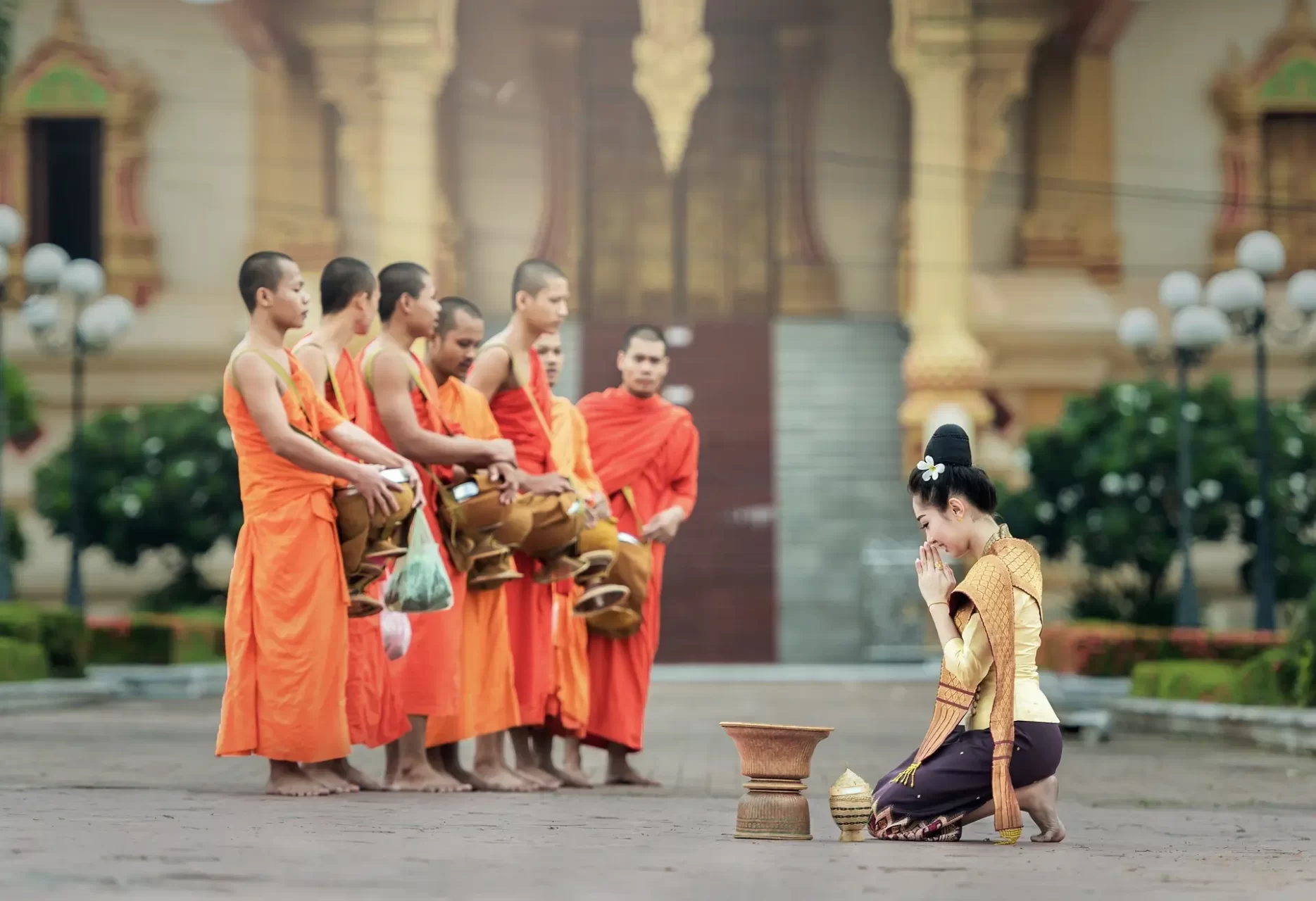 Un momento di devozione quotidiana in Laos, con una donna in vesti tradizionali che fa offerte ai monaci in un rito di generosità e fede.