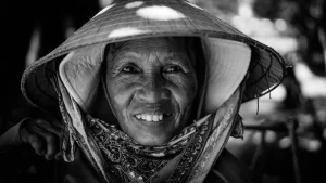 Primo piano di una donna vietnamita che indossa un cappello conico Non La, in bianco e nero.