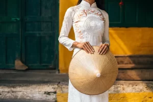 Dettaglio di una donna che indossa l'Ao Dai bianco e tiene un cappello conico Non La