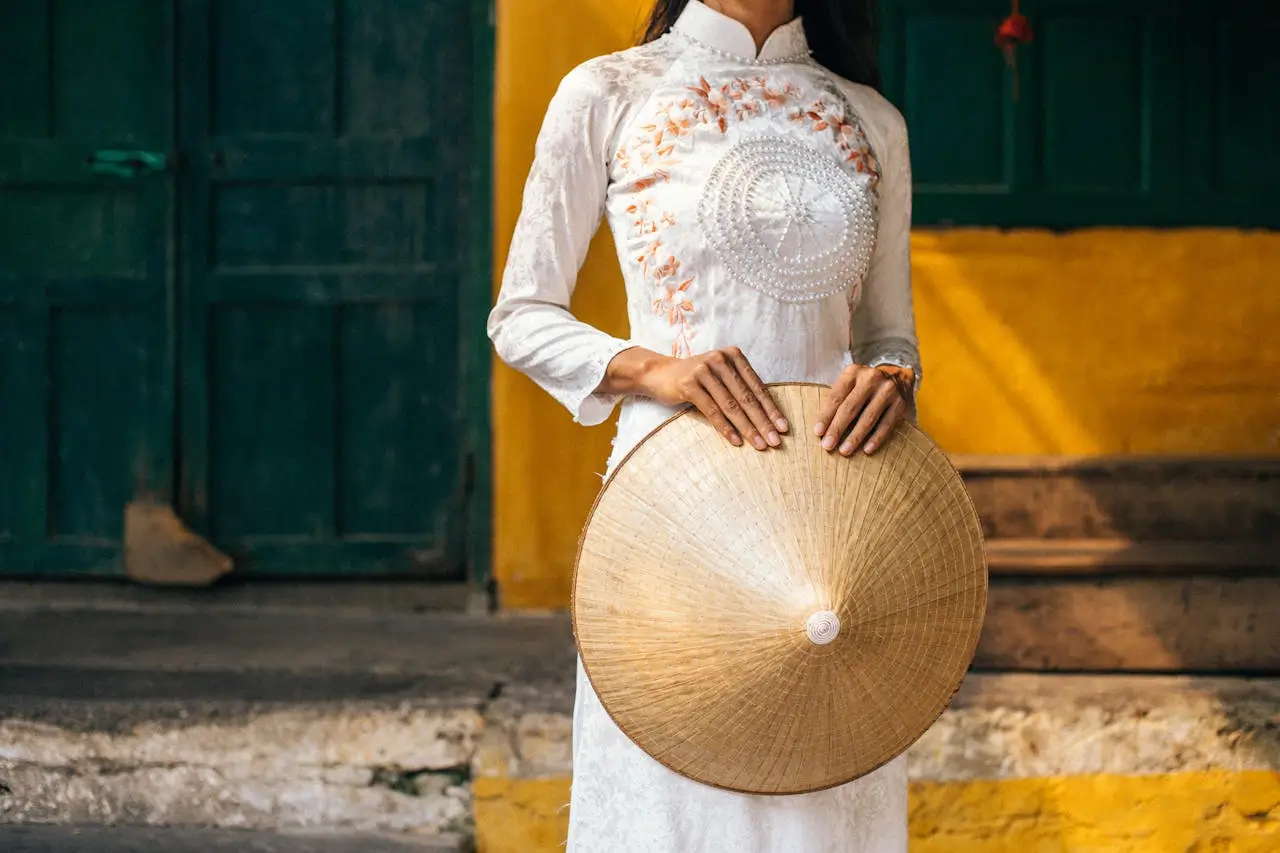 Il Non La, l'Iconico Cappello del Vietnam 109 Dettaglio di una donna che indossa l'Ao Dai bianco e tiene un cappello conico Non La