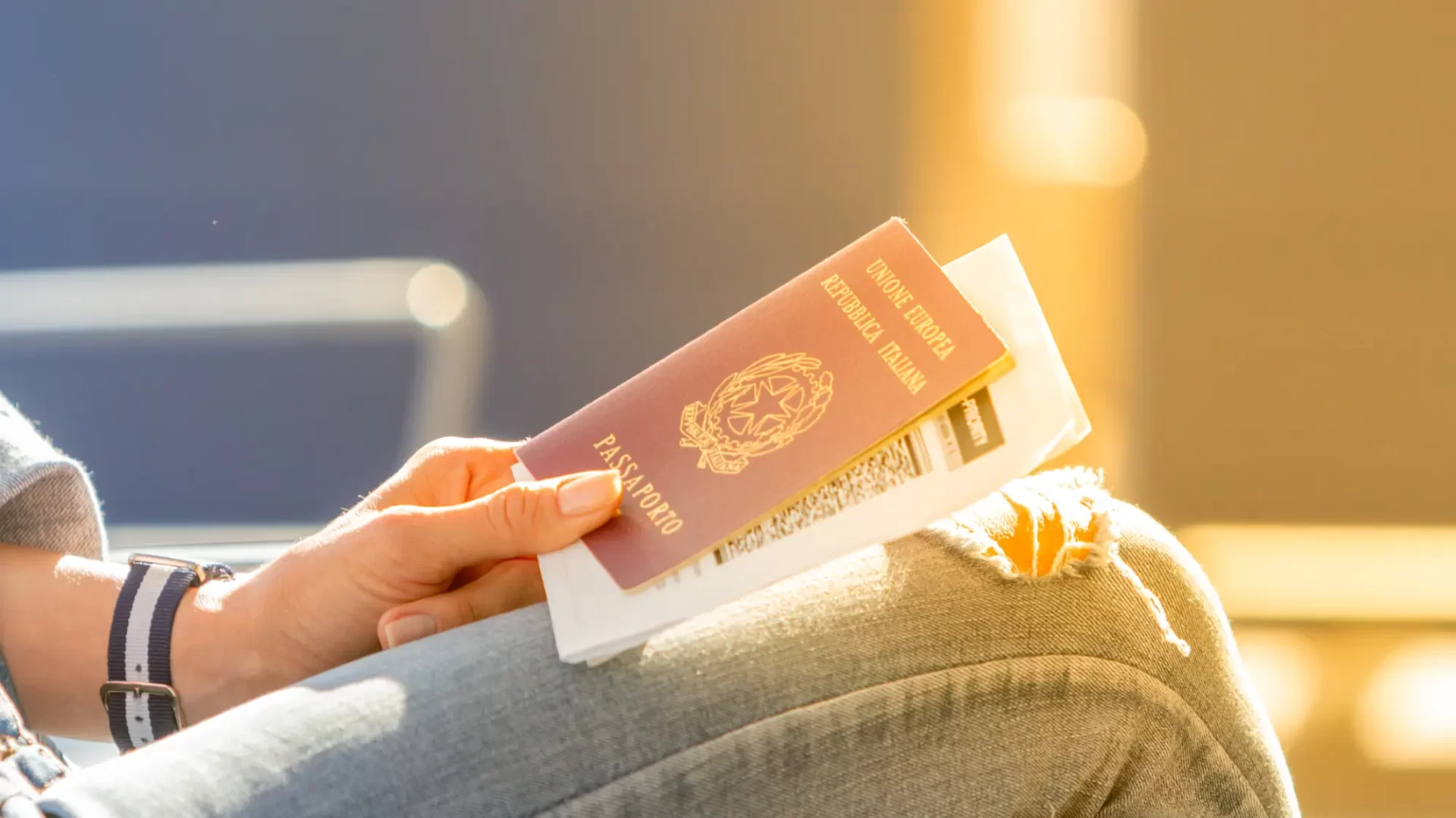 Primo piano di una mano che tiene un passaporto italiano e un biglietto aereo, pronto per il viaggio in Vietnam.