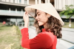 Ritratto di una giovane donna vietnamita sorridente che indossa un cappello conico Non La.