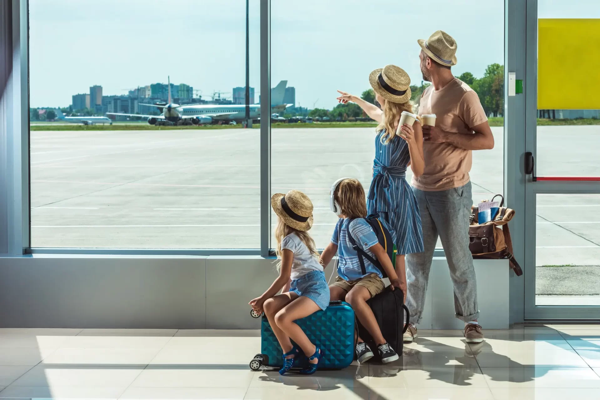 Famiglia con bambini in attesa di imbarcarsi in aeroporto per il Laos, osservando gli aerei attraverso una grande finestra