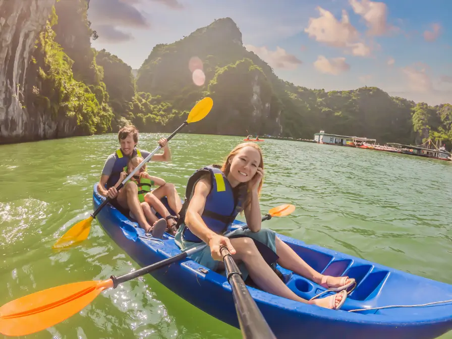  Famiglia felice che fa kayak nelle acque calme della baia di Halong, con maestose montagne sullo sfondo e un cielo limpido.