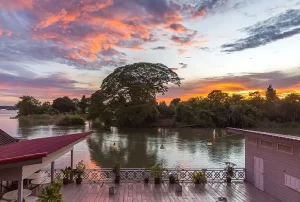 Vista di un suggestivo tramonto con nuvole colorate sopra il fiume Mekong, osservato da una terrazza in legno a Si Phan Don, Laos